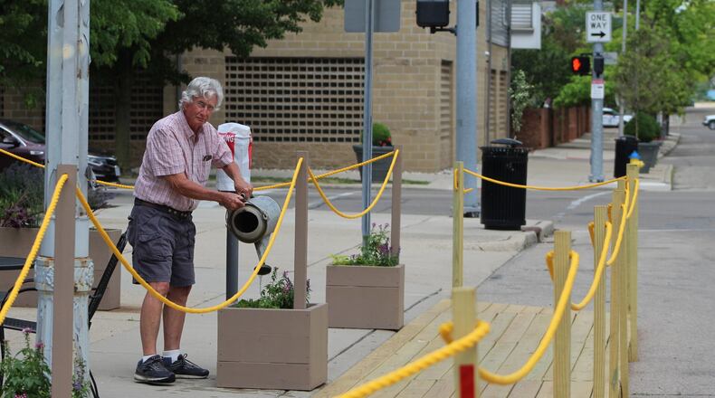 Kelly Williams, 77, waters the plants outside of Mudlick Tap House in downtown Dayton. His son, Forrest Williams, is co-owner of the restaurant, which has expanded its outdoor seating using a patio starter kit. CORNELIUS FROLIK / STAFF
