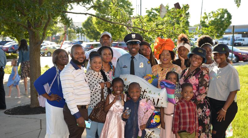 Newly graduated Dayton Police officer Bibebibyo “Bibe” Seko and his mom Sela (orange head wrap) surrounded by their family at Bibe’s graduation. (Photo by Gary Laughlin)