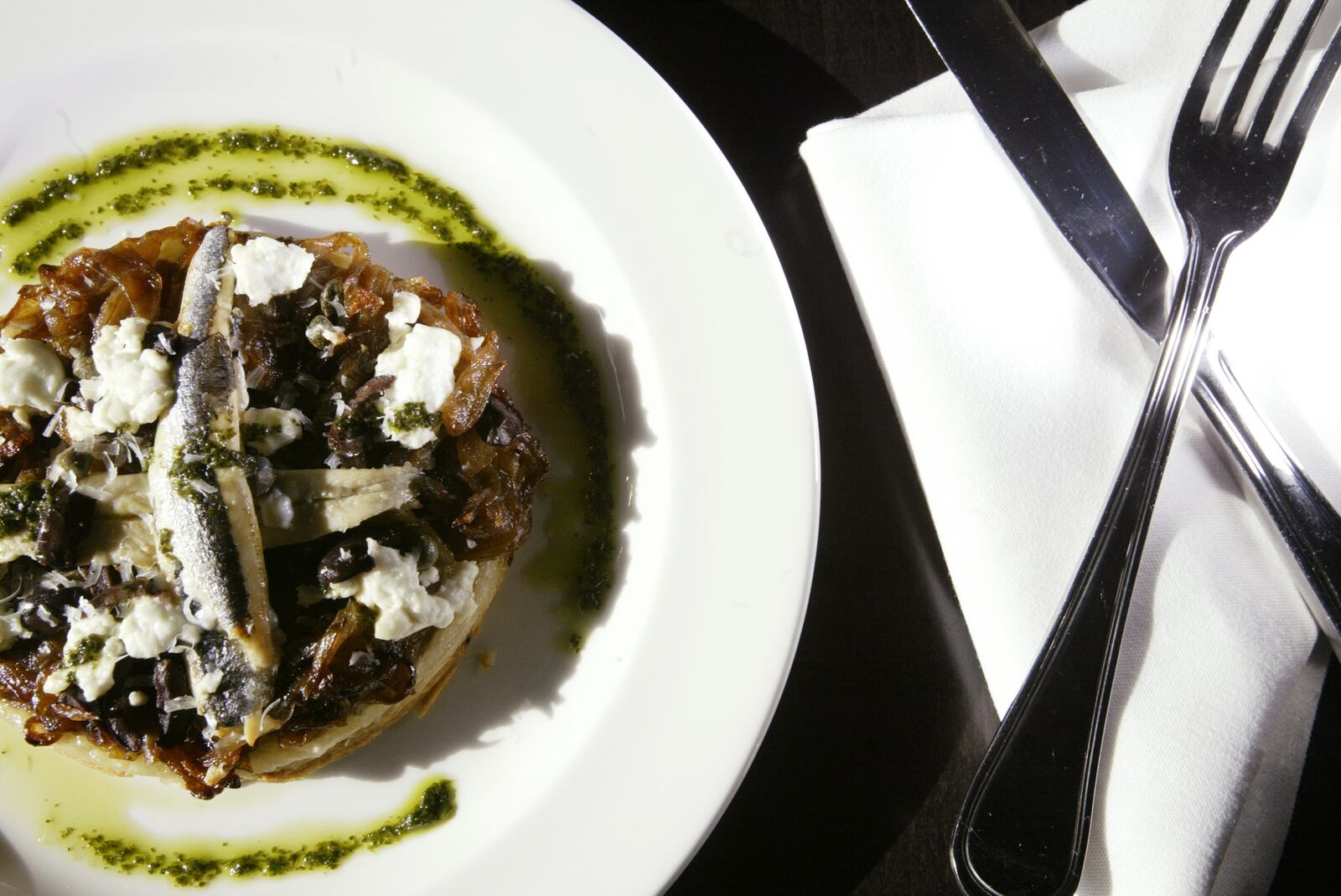 Pissaladiere is a flaky puff pastry tartlet topped with roasted garlic puree, caramelized onions, Nicoise olives and fresh goat cheese, garnished with white anchovies for $7.50 at Rue Dumaine at 1061 Miamisburg-Centerville Road in Centerville. Rue Dumaine is open dinner 5-9:30 p.m. Tuesday-Thursday; 5-10 p.m. Friday and Saturday. Open for lunch 11:30 a.m.-2 p.m. Friday only beginning Jan. 4. 
Staff Photo by Teesha McClam