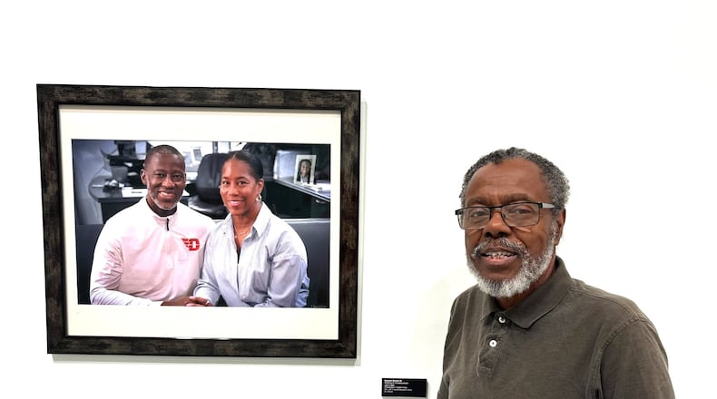 Horace Dozier Sr. stands near his Dayton Skyscraper photo honoring Anthony and Chris Grant and their daughter Jayda seen in the picture behind them. TOM ARCHDEACON/CONTRIBUTED