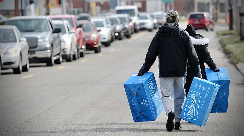 Bobby and Carolyn Allen carry their cases of Mikesell's potato chips down Stanley Avenue to the car that they parked down the block Thursday March 2, 2023. MARSHALL GORBY \STAFF