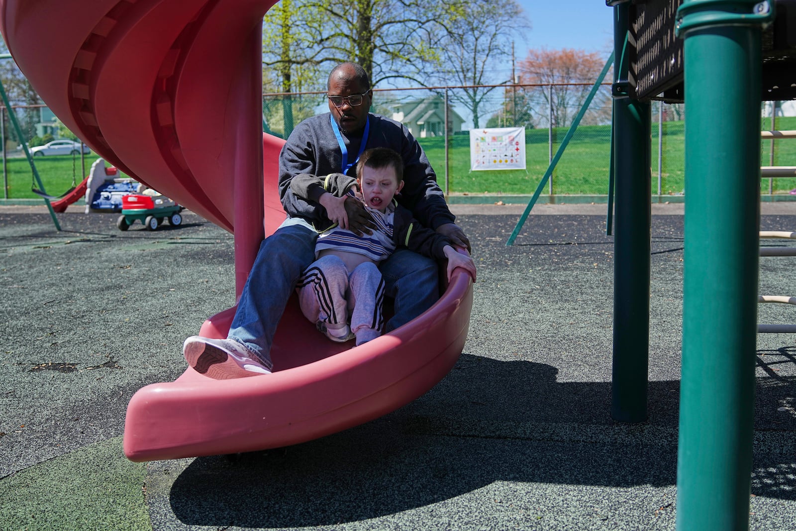 Mark takes a ride on a slide with paraprofessional Raheem Morton at Archbishop Damiano School in Westville, N.J., Wednesday, April 9, 2025. (AP Photo/Matt Rourke)