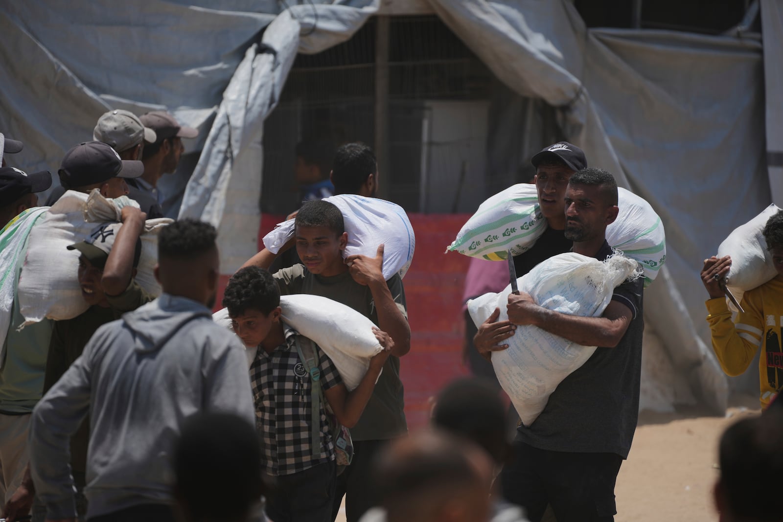 Palestinians carry bags containing food and humanitarian aid packages delivered by the Gaza Humanitarian Foundation, a U.S.-backed organization, in Rafah, southern Gaza Strip, Sunday, June 8, 2025. (AP Photo/Abdel Kareem Hana)