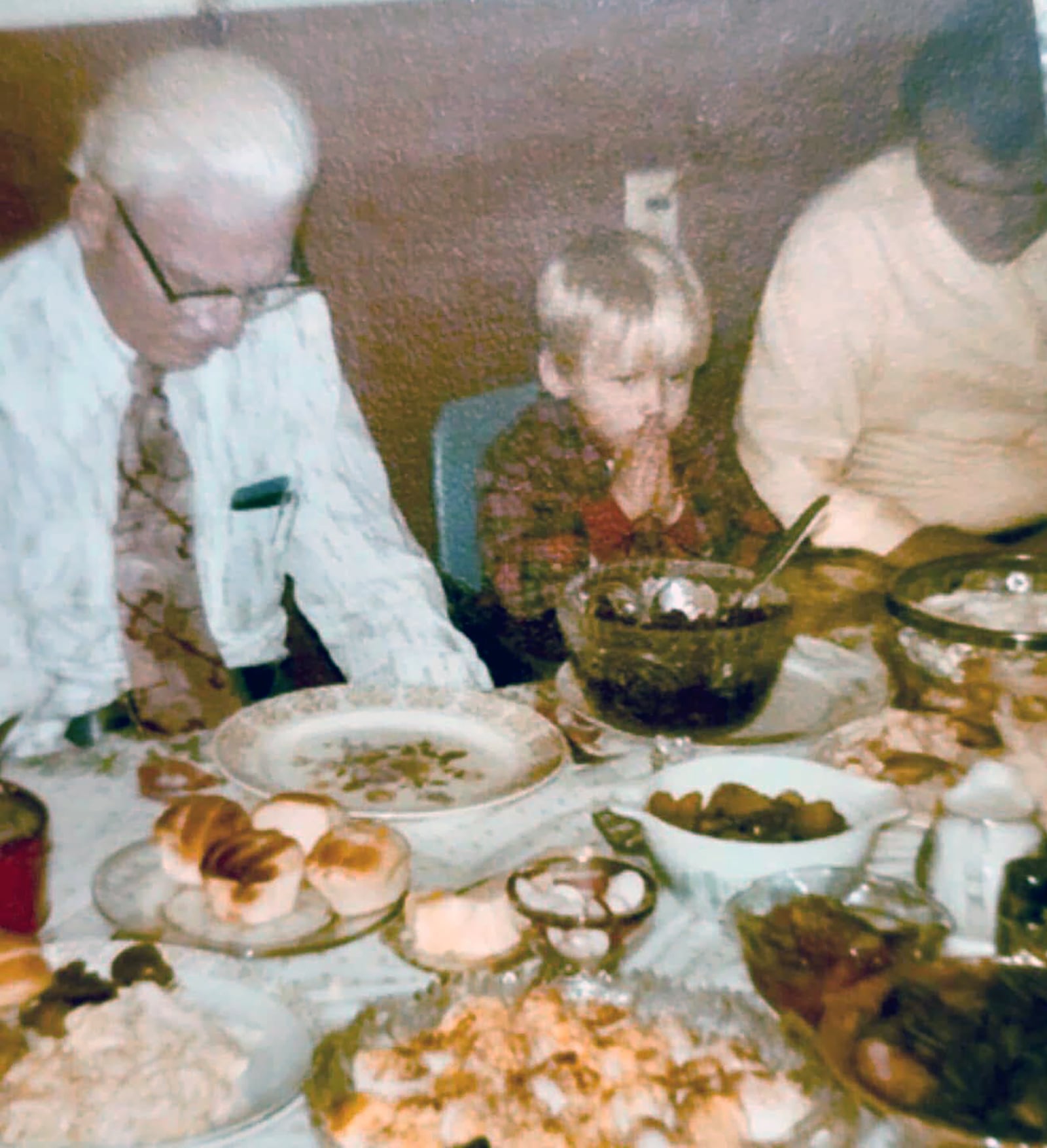 Scott Fussnecker (age 3 - Center) with his grandfather (Left) Reverend James E. Harrington and father (right) Reverend Simon R. Fussnecker praying together before a meal. Fussnecker is a third-generation pastor. CONTRIBUTED