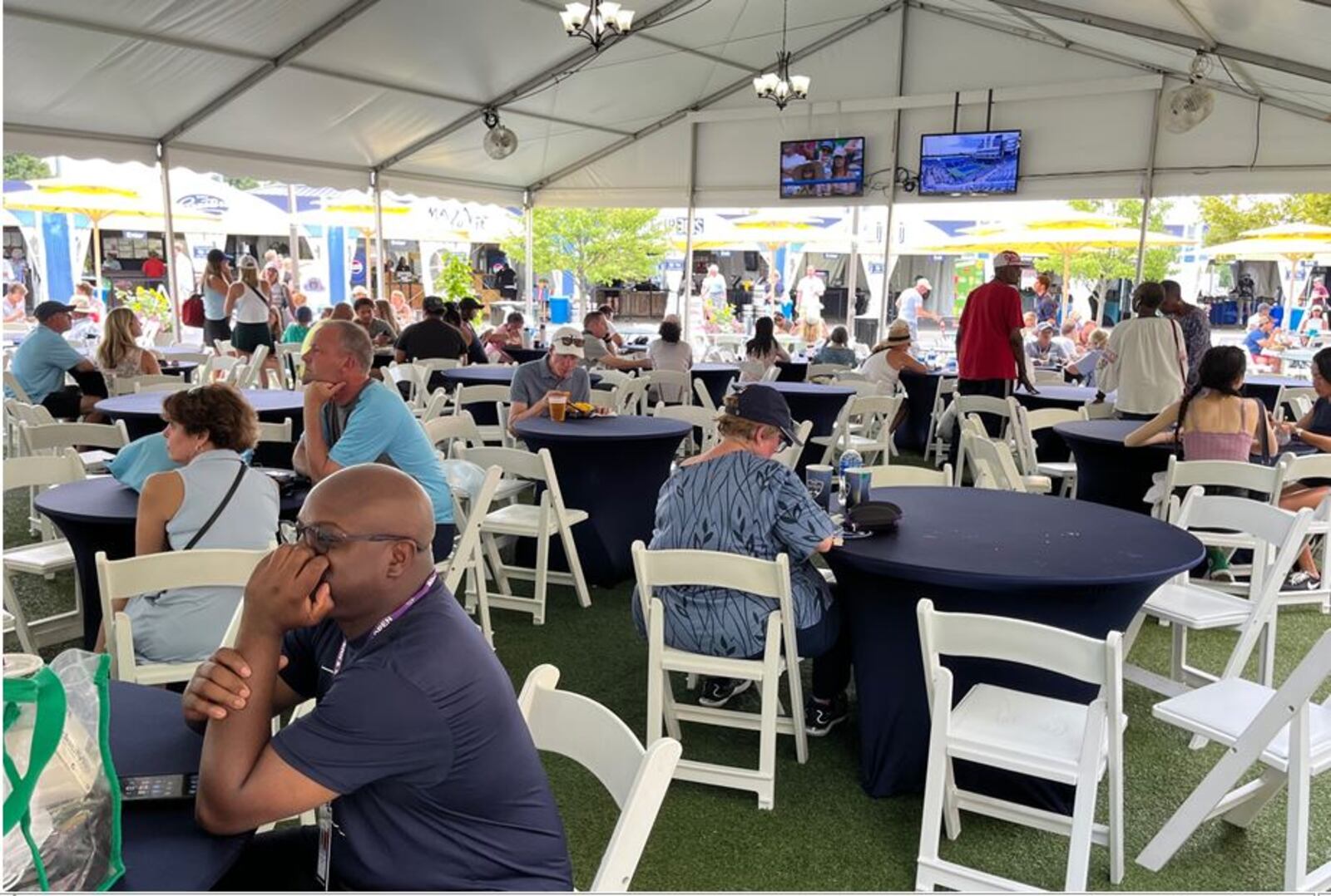 Tennis fans can watch the tennis action on monitors in one of several pavilions that have tables and chairs as they enjoy food and beverages at the Western & Southern Open in Mason.  ED RICHTER/STAFF