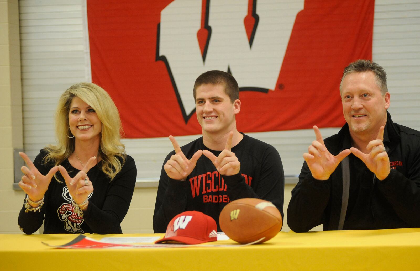 Alter's Kraig Howe and his mother and father flash the Wisconsin logo, where he'll play college football. Alter High School held a National Signing Day ceremony on Wednesday, Feb. 4, 2015.   RELATED: Area signing list for 2015-16   |   Photos: Past area signing day athletes   |   Complete Signing Day coverage