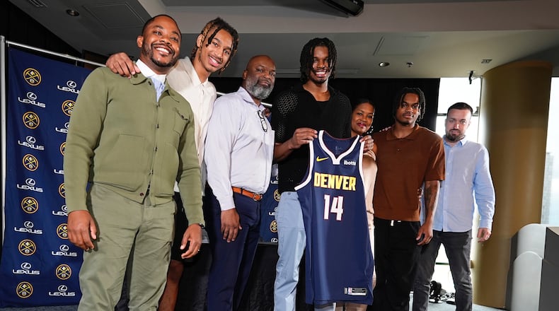 Denver Nuggets 2024 first-round draft pick DaRon Holmes II, center, holds up his jersey for a photograph with, from left, business manager Mitch Brown, brother Cameron Holmes, father DaRon, Sr., mother Tomika, brother Quintyn and agent Aaron Reilly during an NBA basketball news conference Monday, July 1, 2024, in Denver. (AP Photo/David Zalubowski)