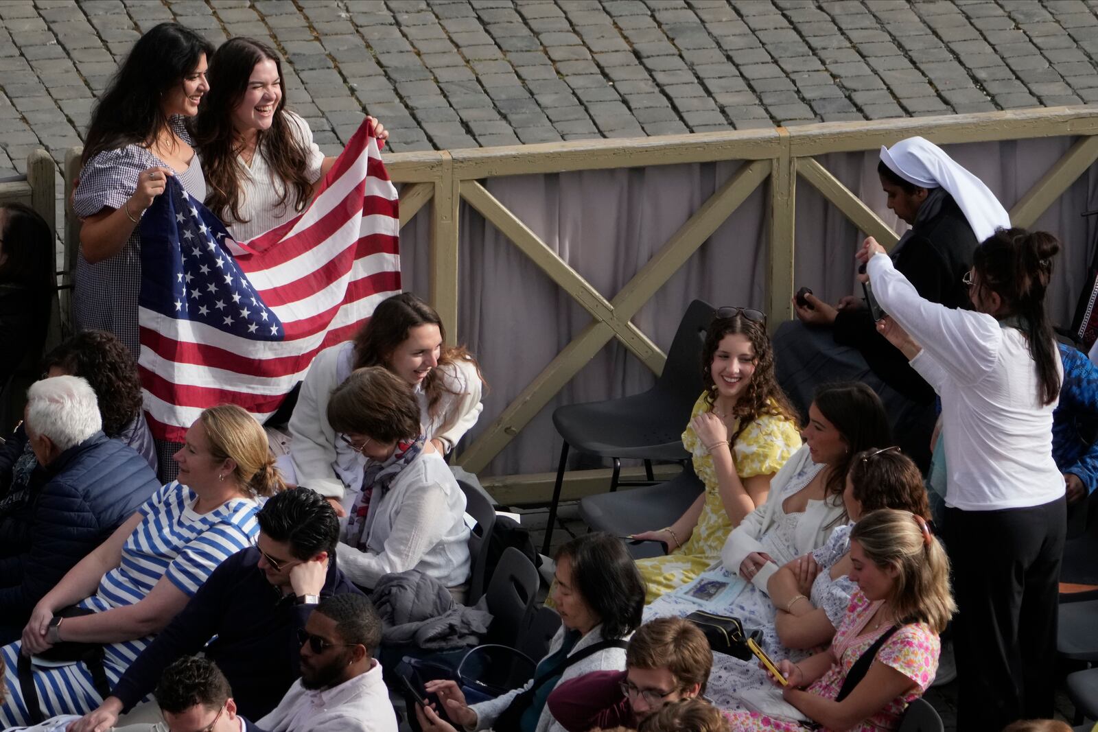 Faithful pose with a United States' flag as they wait for the start of the Easter mass in St. Peter's Square at the Vatican Sunday, April 20, 2025. (AP Photo/Gregorio Borgia)