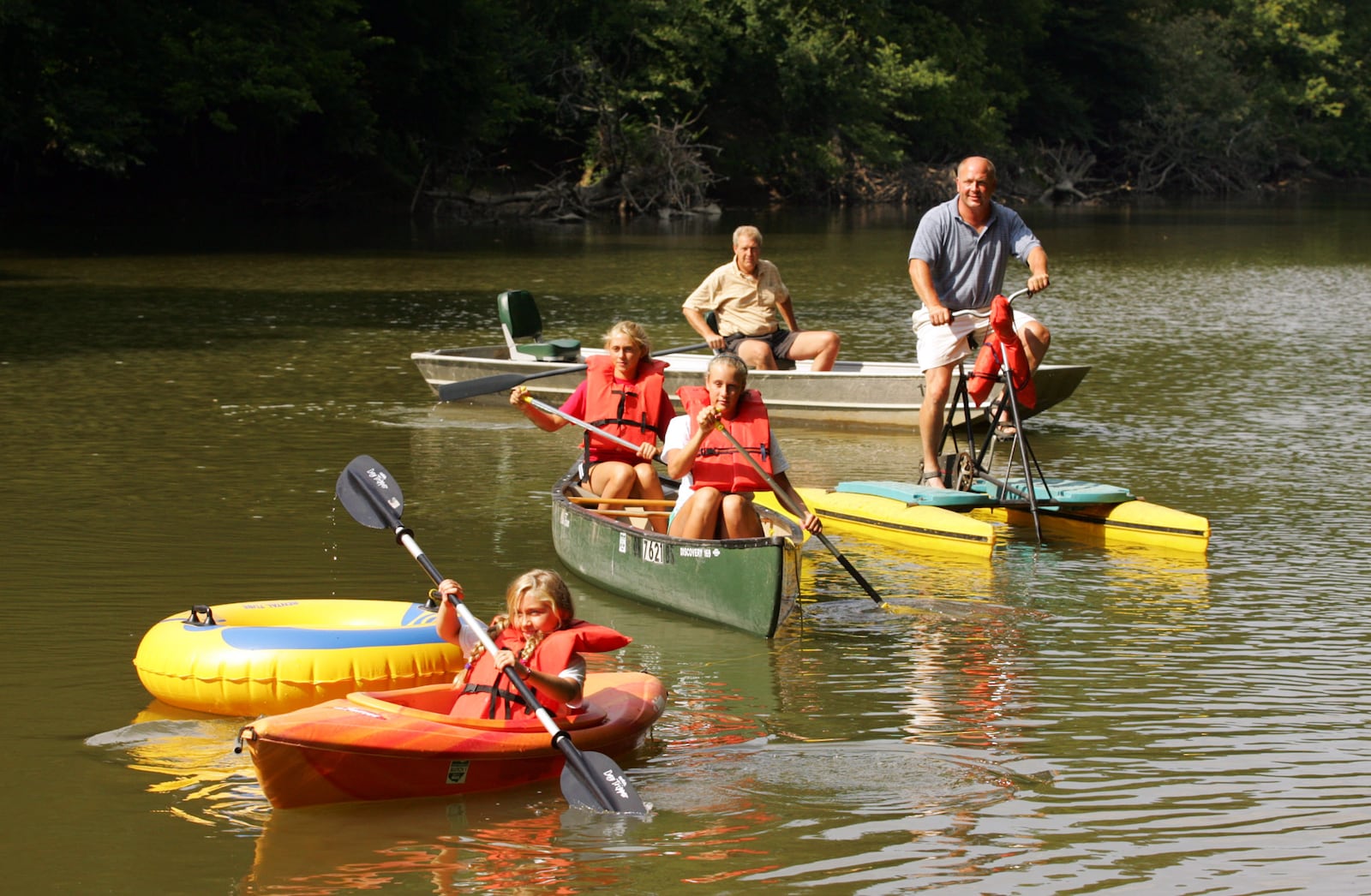 Demonstrating canoes, kayaks, boats, and recreational devices from Great Miami Adventures canoe livery near Tipp City on Ross Road are front to back: Kayte (cq) Jackson, Grace Kauth and Sidney Jackson, Chris Jackson, and Joe Jackson. Chris Jackson is the owner of the new business that includes a grounds for group events, or camping. Staff Photo by Jim Witmer