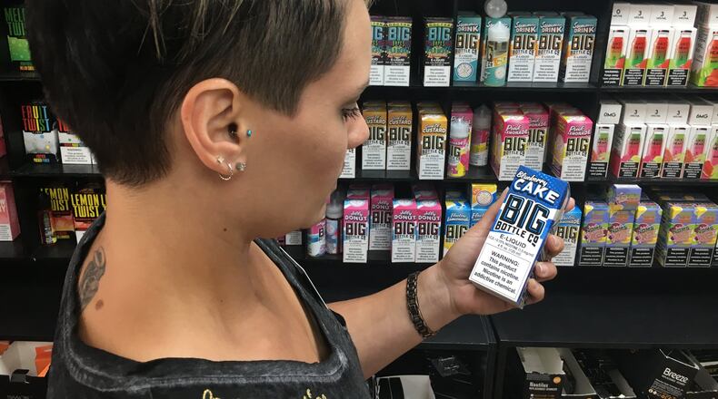 Vapor Haus General Manager Kris Rugg shows some of the e-liquid products that they advocates say help smokers quit cigarettes. STAFF PHOTO / HOLLY SHIVELY