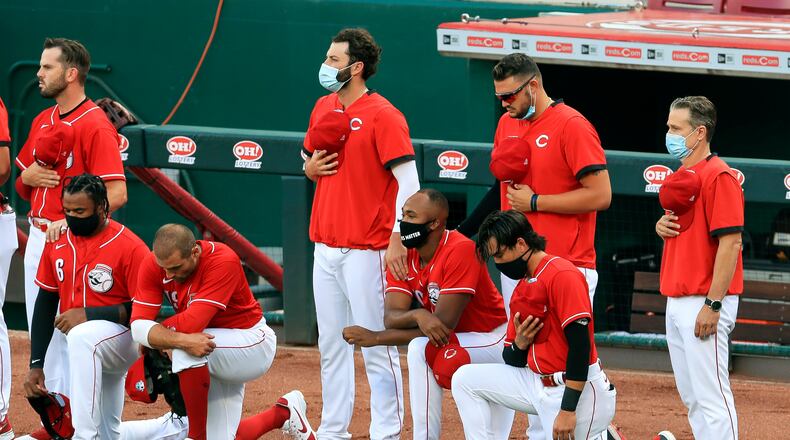 Cincinnati Reds' Phillip Ervin, left, Joey Votto, left middle, Amir Garrett, middle, and Alex Blandino, right, kneel during the national anthem prior to an exhibition baseball game against the Detroit Tigers at Great American Ballpark in Cincinnati, Tuesday, July 21, 2020. (AP Photo/Aaron Doster)