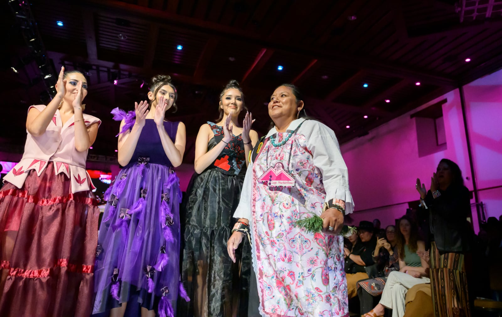 Designer Sage Mountainflower, right, receives a round of applause after her runway show at the 2025 Native Fashion Show, Friday, May 9, 2025, in Santa Fe, N.M. (AP Photo/Roberto E. Rosales)
