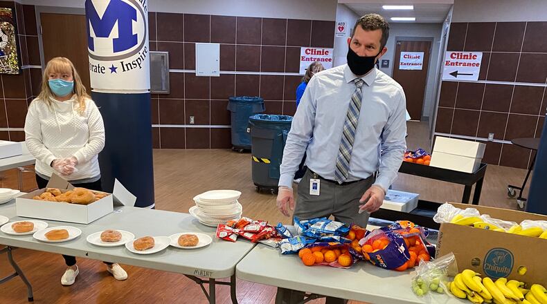 Miamisburg High School Principal Michael Black and school counselor Sheanna Kurtz hand out donated donuts, fruit, snacks and drinks before school Thursday, Nov. 12. The school's entire cafeteria staff had to quarantine on very short notice, but school employees and community members stepped up to fill the need. CONTRIBUTED PHOTO