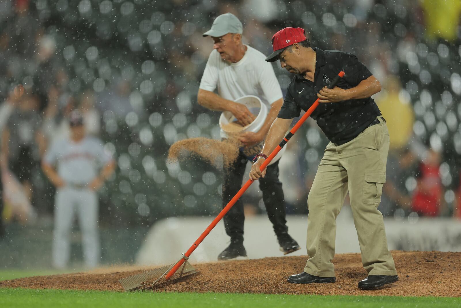 Members of the Chicago White Sox grounds crew fixes the mound as rain falls during the ninth inning in the second baseball game of a doubleheader against the Cleveland Guardians, Friday, July 11, 2025, in Chicago. (AP Photo/Melissa Tamez)