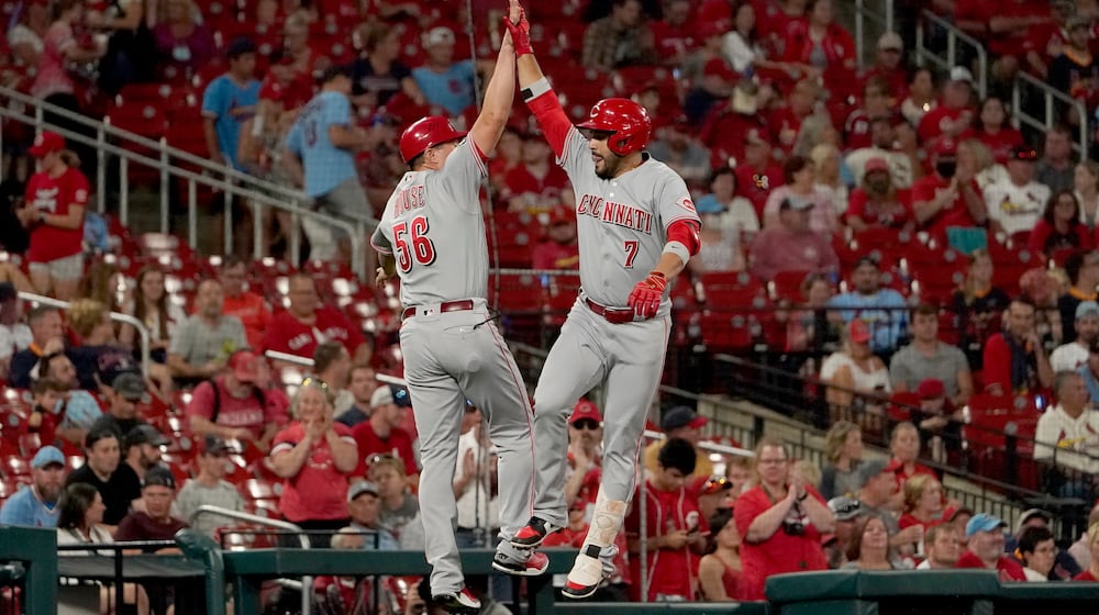 Cincinnati Reds' Eugenio Suarez (7) is congratulated by third base coach J.R. House while rounding the bases after hitting a solo home run during the second inning of a baseball game against the St. Louis Cardinals Friday, Sept. 10, 2021, in St. Louis. (AP Photo/Jeff Roberson)