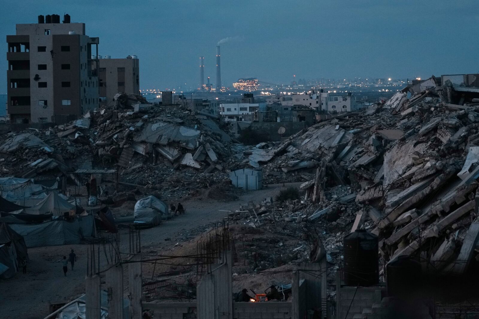 Palestinians displaced by the Israeli air and ground offensive on the Gaza Strip stand surrounded by destroyed buildings during the dusk in an area in Gaza City, Monday, June 2, 2025. (AP Photo/Jehad Alshrafi)