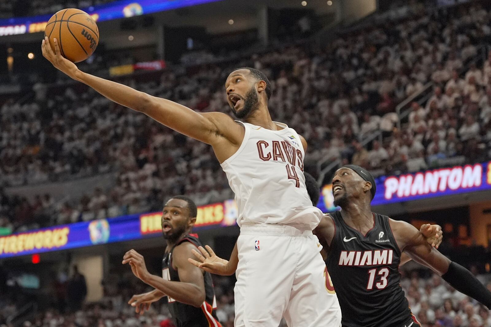Cleveland Cavaliers forward Evan Mobley (4) reaches for a rebound between Miami Heat forward Andrew Wiggins, left, and center Bam Adebayo (13) in the first half in Game 2 of an NBA first-round playoff series, Wednesday, April 23, 2025, in Cleveland. (AP Photo/Sue Ogrocki)