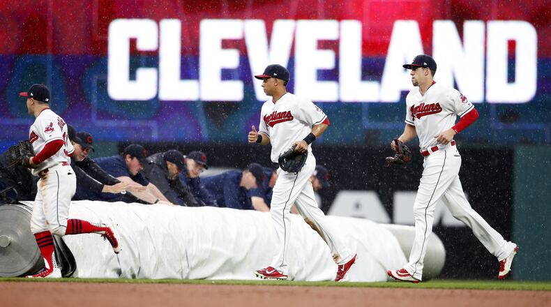CLEVELAND, OH - MAY 24: Daniel Robertson #99 Michael Brantley #23 and Bradley Zimmer #4 of the Cleveland Indians run to the dugout as the grounds crew rolls out the tarp due to heavy rain against the Cincinnati Reds during the sixth inning at Progressive Field on May 24, 2017 in Cleveland, Ohio. (Photo by Ron Schwane/Getty Images)