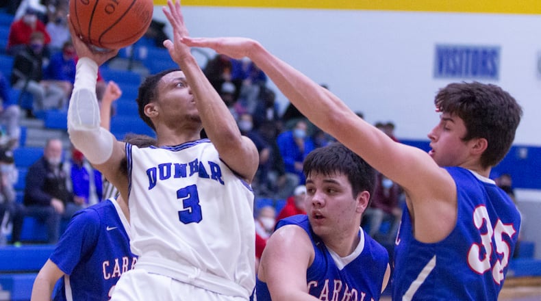 Dunbar's Chanze Amerson puts up a tough shot that goes in as he was fouled by Carroll's Johnny Deep during a February 2021 game against Carroll High School. Jeff Gilbert/CONTRIBUTED