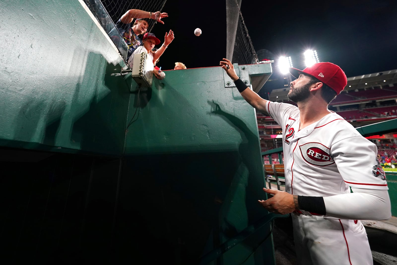 Cincinnati Reds center fielder Tyler Naquin (12) signs autographs for fans at the conclusion of a baseball game against the St. Louis Cardinals, Monday, Aug. 30, 2021, at Great American Ball Park in Cincinnati. The St. Louis Cardinals won, 3-1. (Kareem Elgazzar/The Cincinnati Enquirer via AP)