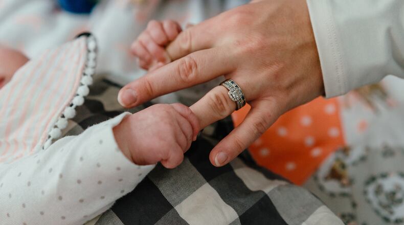 The tiny hands of infant Natalie Berg, who contracted RSV (respiratory syncytial virus), grip the fingers of her mother, Dr. Caitlyn Berg, a pediatrician, at their home in Mount Zion, Ill., Oct. 30, 2022. Early data from the CDC's New Vaccine Surveillance Network show nirsevimab is 90% effective in preventing infants from being hospitalized with RSV. (Jamie Kelter Davis/The New York Times)
