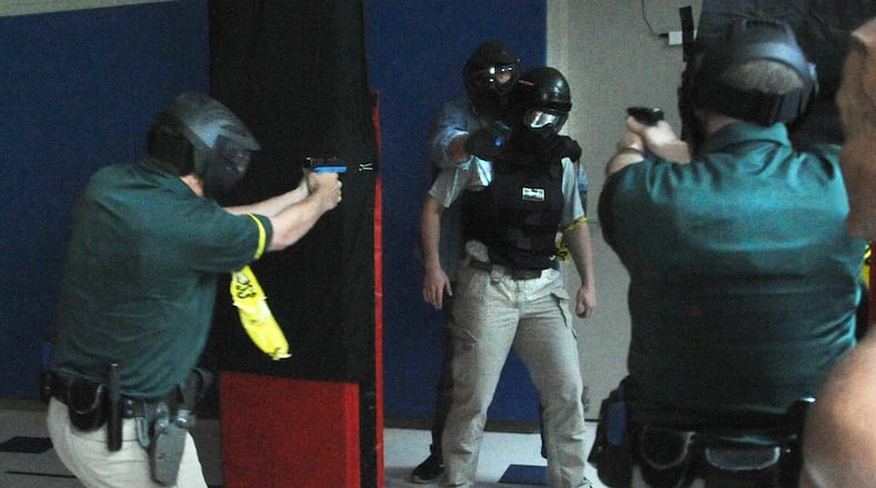 Cadets Chris Jones and Noah Wollum face off against Sinclair Police Academy Commander Joe Niehaus in a mock domestic dispute situation at Sinclair Police Academy. Reporter London Bishop is the hostage in this scenario. MARSHALL GORBY\STAFF