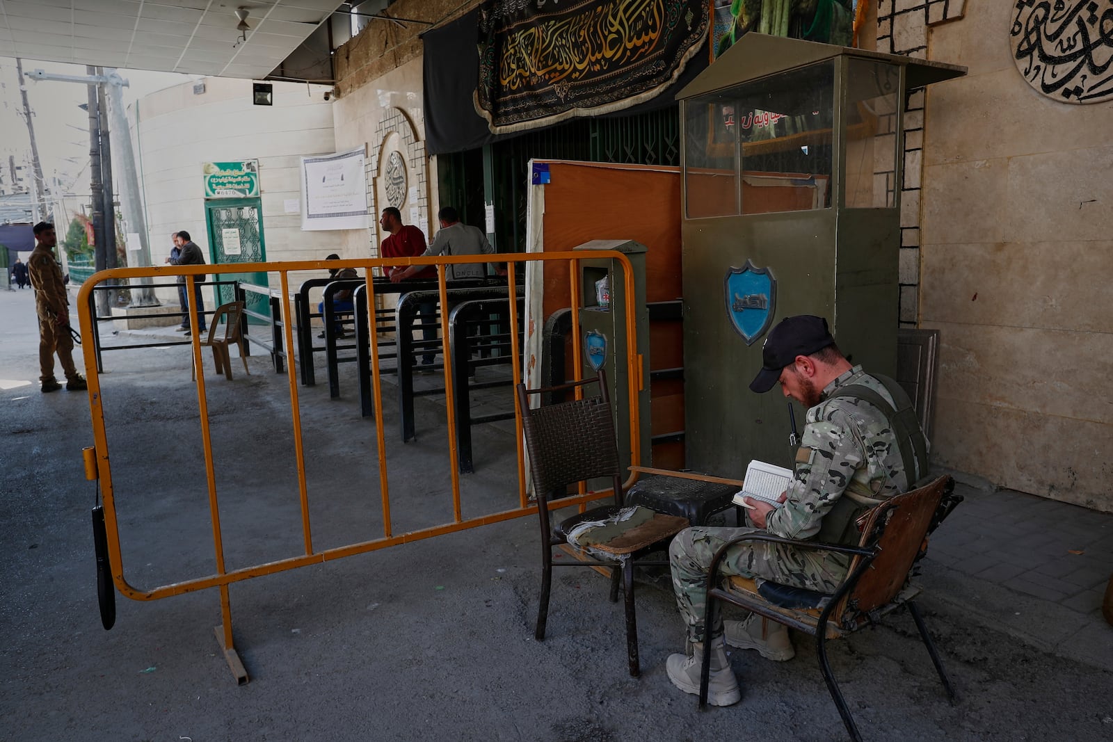 A soldier from the Syrian government army reads the Quran, the Muslim holy book, at a checkpoint near the Sayyida Zeinab Shrine, where many Shiite Muslims believe Zeinab, the granddaughter of the Prophet Muhammad, is buried, in Sayyida Zeinab, south of Damascus, Syria, Saturday, March 15, 2025. (AP Photo/Omar Sanadiki)