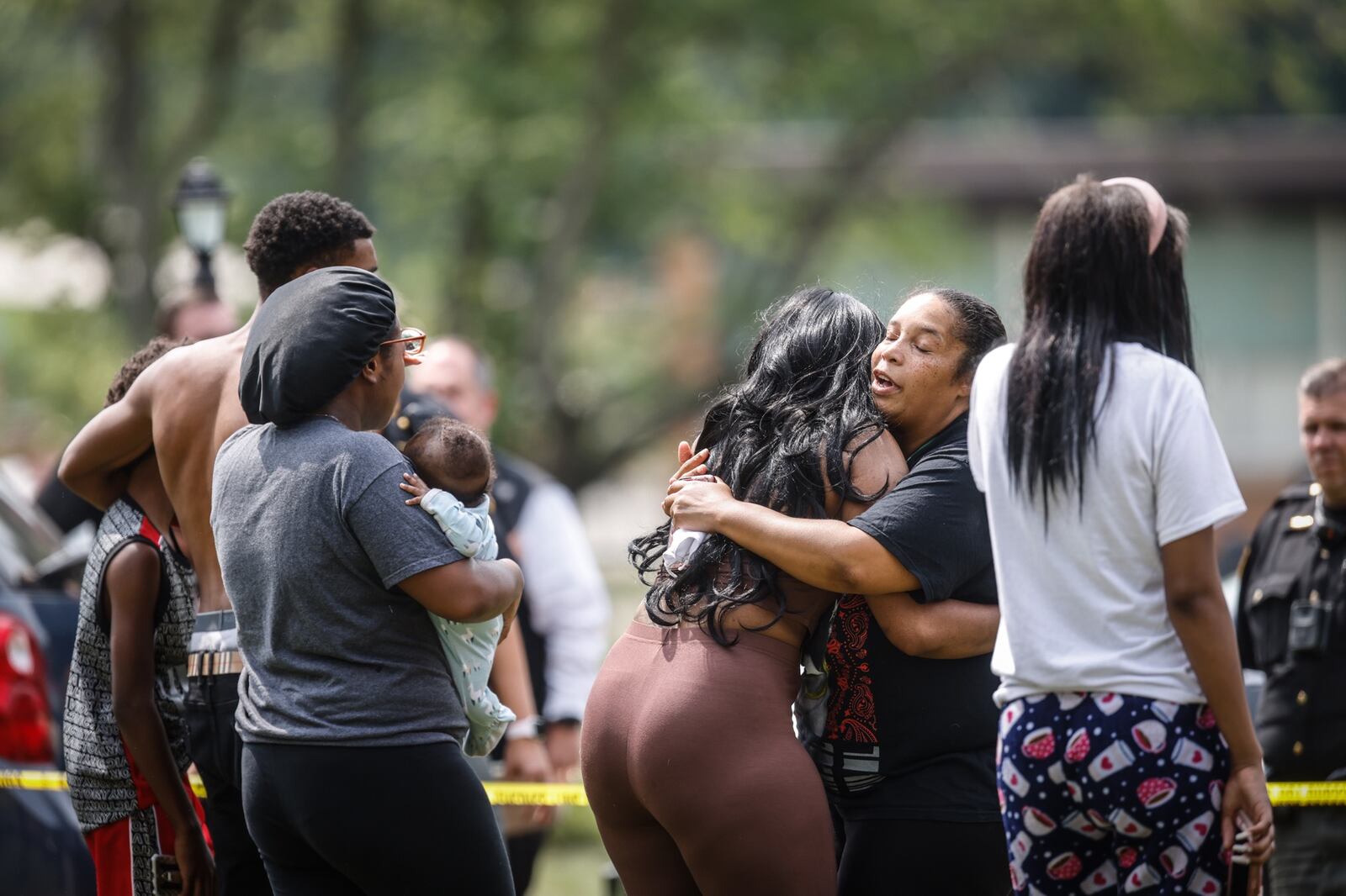 People embrace outside a home after a person was reported shot Friday afternoon, Aug. 6, 2021, inside the home in the 4900 block of Ericson Avenue in Jefferson Twp. JIM NOELKER/STAFF