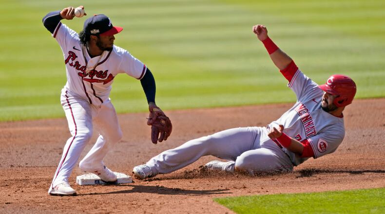 Atlanta Braves second baseman Ozzie Albies (1) throws to first after forcing out Cincinnati Reds' Eugenio Suarez (7) during the second inning in Game 2 of a National League wild-card baseball series, Thursday, Oct. 1, 2020, in Atlanta. The Reds' Mike Moustakas was safe at first. (AP Photo/John Bazemore)