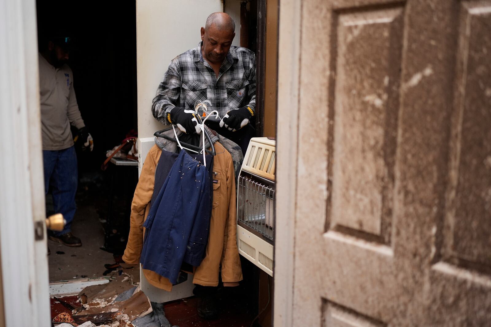 Willy Barns gathers cloths at his house after severe weather passed the area in Selma, Tenn., Thursday, April 3, 2025. (AP Photo/George Walker IV)