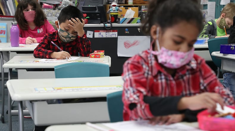With masks and desks spaced apart, young students at Simon Kenton Elementary School in Xenia work on classwork Feb. 19, 2021. BILL LACKEY/STAFF