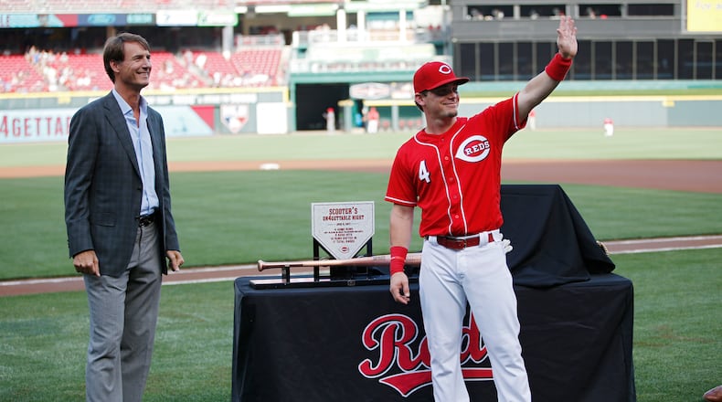Scooter Gennett of the Reds waves to fans while standing with general manager Dick Williams during a ceremony to commemorate his four home run game from June 6 prior to a game against the Los Angeles Dodgers at Great American Ball Park.