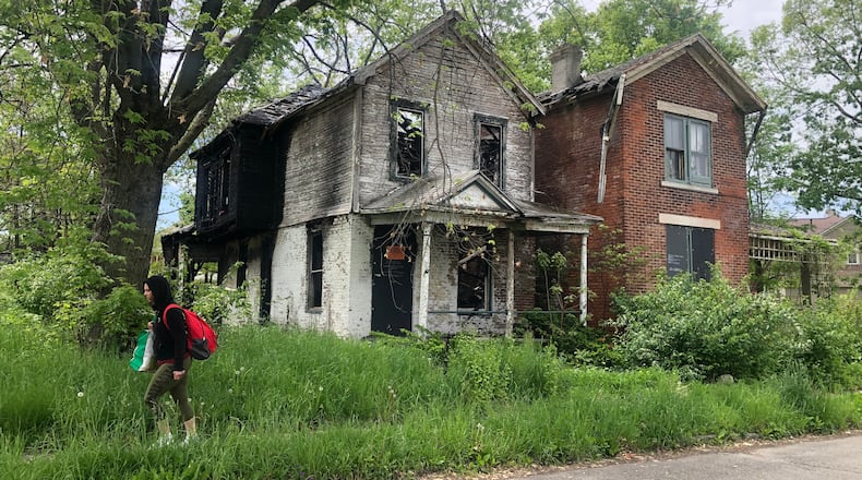 Dayton plans to demolish about 850 housing units using more than $15 million in federal rescue funds. A woman walks by two abandoned and vacant homes in East Dayton. CORNELIUS FROLIK / STAFF