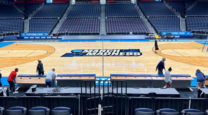 Workers on Sunday put the finishing touches on the basketball court installation for the First Four of the NCAA Division I Men’s Basketball Championship at UD Arena. AIMEE HANCOCK/STAFF