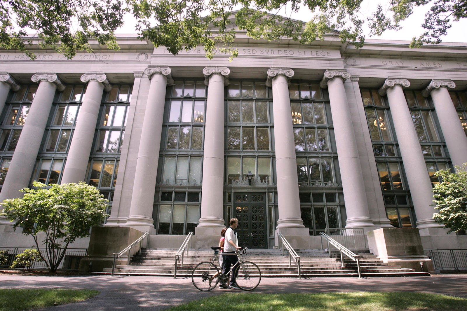 FILE - A bicyclist walks by Langdell Hall, the Harvard Law Library, on the Harvard Law School campus at Harvard University, Aug. 1, 2005, in Cambridge, Mass. (AP Photo/Charles Krupa, File)