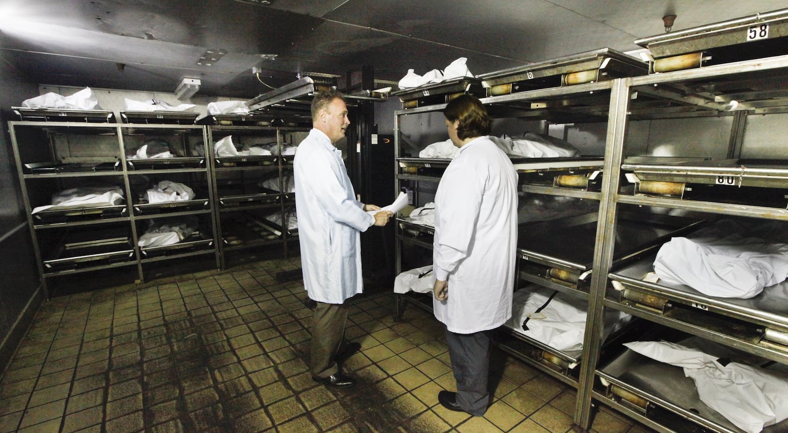 Montgomery County Coroner Dr. Kent Harshbarger, left, and pathology technician Michelle Welch inside the cooler at the morgue. CHRIS STEWART / STAFF
