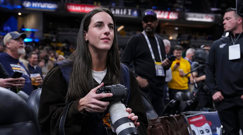 Indiana Fever guard Caitlyn Clark takes photos during pregame before an NBA basketball game between the Indiana Pacers and the Los Angeles Lakers in Indianapolis, Wednesday, March 25, 2026. (AP Photo/Michael Conroy)