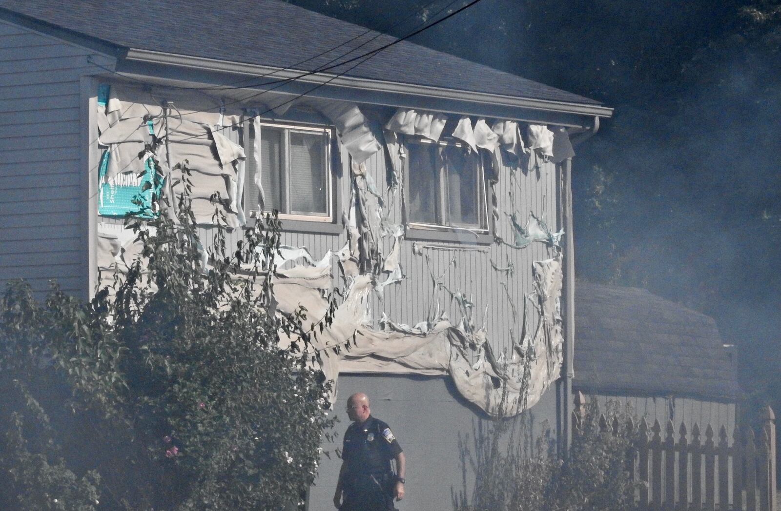 Siding is damaged on a neighbor’s house Wednesday morning as Middletown firefighters battled a fire engulfed in flames. NICK GRAHAM/STAFF