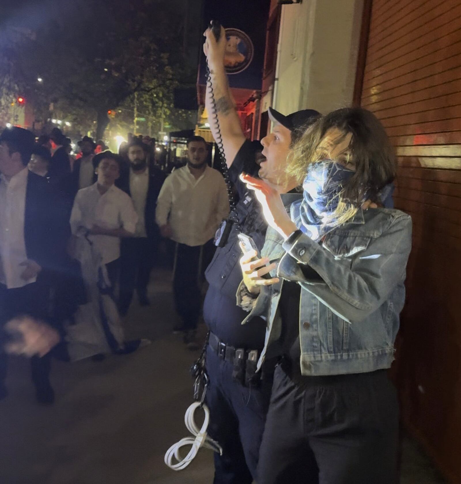 This image taken from video shows a woman and a police officer as they are pursued by a crowd of men in the Crown Heights section of Brooklyn, N.Y., on Thursday, April 24, 2025. (AP Photo)