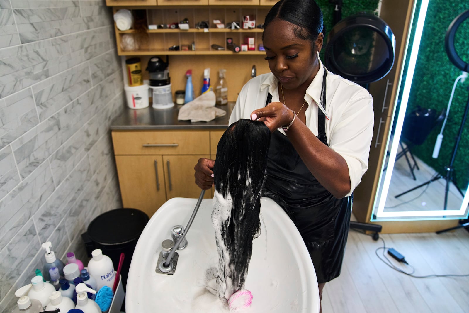 Dajiah Blackshear, a natural hair stylist who specializes in extensions, washes a client's wig during an installation service, Monday, May 5, 2025, at her salon suite in Atlanta. (AP Photo/Stephanie Scarbrough)