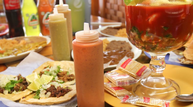 A spread of adventurous food at Taqueria Mixteca mexican restaurant at 1609 E. Third St., Dayton. Foreground shows Huarche, background left are three different meat tacos and on right in glass bowl is Seafood Cocktail.