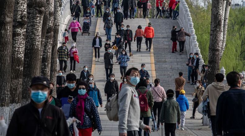 BEIJING, CHINA - APRIL 05: People wear protective masks as they walk while enjoying the spring weather on April 5, 2020 at a park in Beijing, China. With the pandemic hitting hard across the world, officially the number of coronavirus cases in China is dwindling, ever since the government imposed sweeping measures to keep the disease from spreading. For more than two months, millions of people across China have been restricted in how they move from their homes, while other cities have been locked down in ways that appeared severe at the time but are now being replicated in other countries trying to contain the virus. Officials believe the worst appears to be over in China, though there are concerns of another wave of infections as the government attempts to reboot the world's second largest economy. In Beijing, it is mandatory to wear masks outdoors, some retail stores still operate on reduced hours, restaurants employ social distancing among patrons, and tourist attractions at risk of drawing large crowds remain closed or allow only limited access. Monitoring and enforcement of virus-related measures and the quarantine of anyone arriving to Beijing is carried out by neighborhood committees and a network of Communist Party volunteers who wear red arm bands. Since January, China has recorded more than 81,000 cases of COVID-19 and at least 3200 deaths, mostly in and around the city of Wuhan, in central Hubei province, where the outbreak first started.