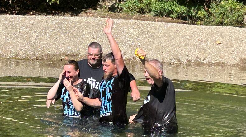 Jacqueline and Bradly Fenker were baptized last Sunday afternoon by Pastor Chuck Hall, left, and Pastor John Ward in Twin Creek. RICK McCRABB/CONTRIBUTOR