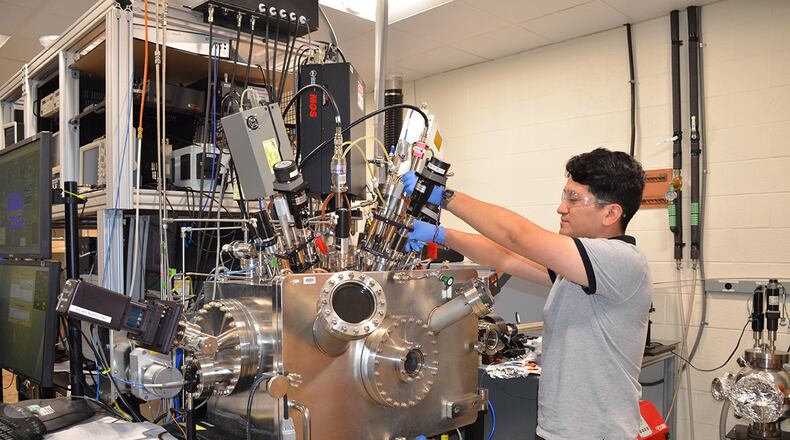 Graduate student from the University of Texas El Paso, Cristian Orozco, works in the Materials and Manufacturing Directorate over the summer. One of his duties includes working with a vacuum chamber for thin film coatings for optics. U.S. AIR FORCE PHOTO/DONNA LINDNER
