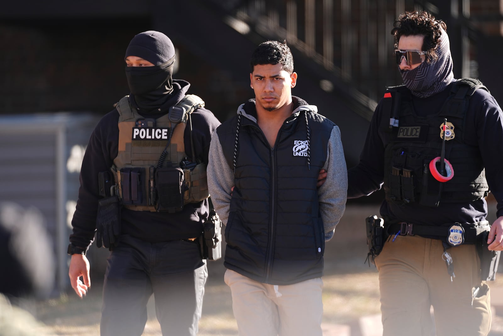 File - Law officials escort a suspect from an apartment to a waiting utility vehicle for transport during a raid Feb. 5, 2025, in east Denver. (AP Photo/David Zalubowski, File)
