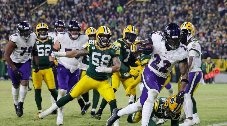 Baltimore Ravens running back Derrick Henry (22) scores a touchdown past Green Bay Packers cornerback Carrington Valentine (24) during the first half of an NFL football game, Saturday, Dec. 27, 2025, in Green Bay, Wis. (AP Photo/Matt Ludtke)
