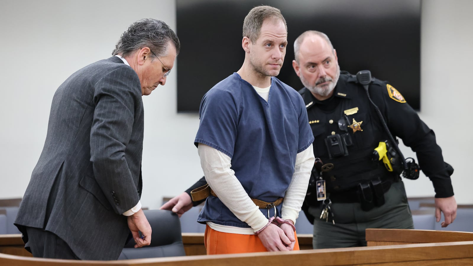 Caleb Flynn (center) sits down shortly after being escorted into a Miami County Common Pleas Court on Thursday, March 19 in Troy. BRYANT BILLING / STAFF