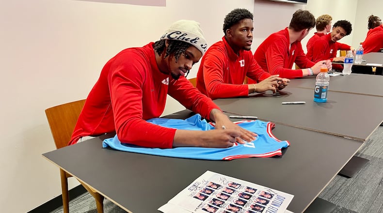 Dayton players DaRon Holmes II, left, and Makai Grant sign autographs before "The Spotlight, To Shine A Light On Mental Health" at UD Arena on Thursday, Oct. 19, 2023. David Jablonski/Staff