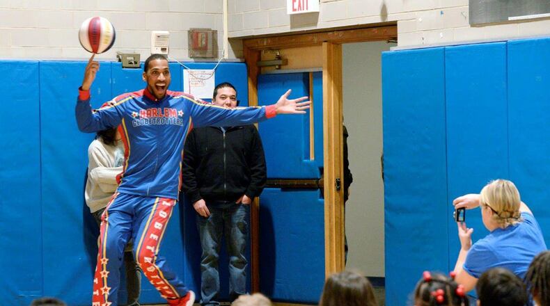 Harlem Globetrotter Zeus McClurkin places a spinning basketball on the finger of 9-year-old Chayna Griffith inside the Prairies Childhood Development Center at Wright-Patterson Air Force Base Dec. 13. McClurkin reviewed the history of the Globetrotters and reminded the students about the importance of teamwork and respecting each other before inviting some of them to participate in basketball tricks. (U.S. Air Force photo/Ty Greenlees)