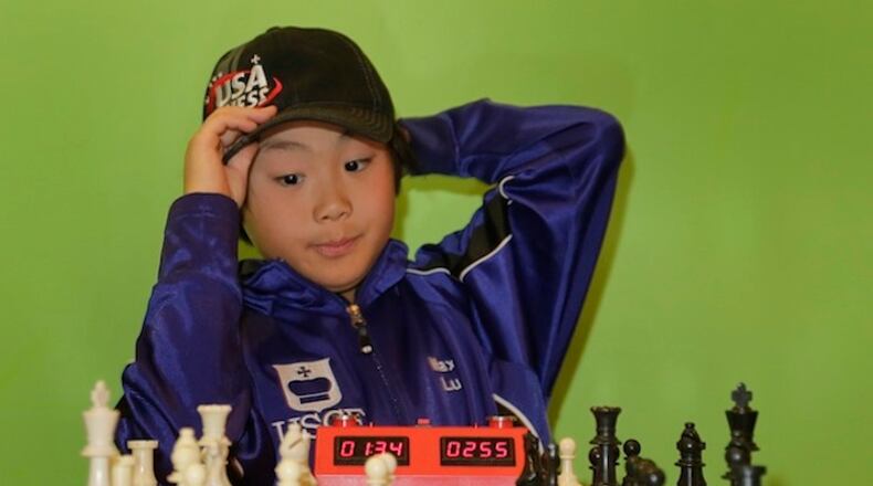 Maximillian Lu adjusts his cap as he toys with a chess set during an interview, Monday, Nov. 16, 2015, in Armonk, N.Y. The 10-year-old recently became the youngest chess master ever in the United States. (AP Photo/Julie Jacobson)